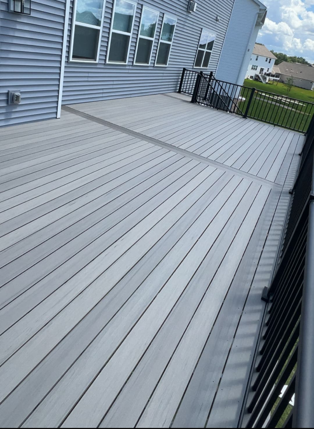 Composite deck with gray planks and black railing, featuring expansive outdoor space.