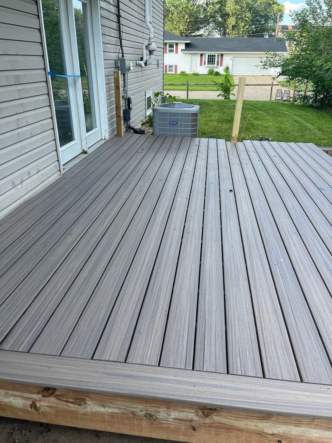 Newly constructed composite deck with modern gray planks next to a house exterior.