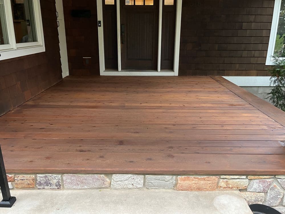 Newly renovated wooden porch with stone accents and a welcoming front entrance.