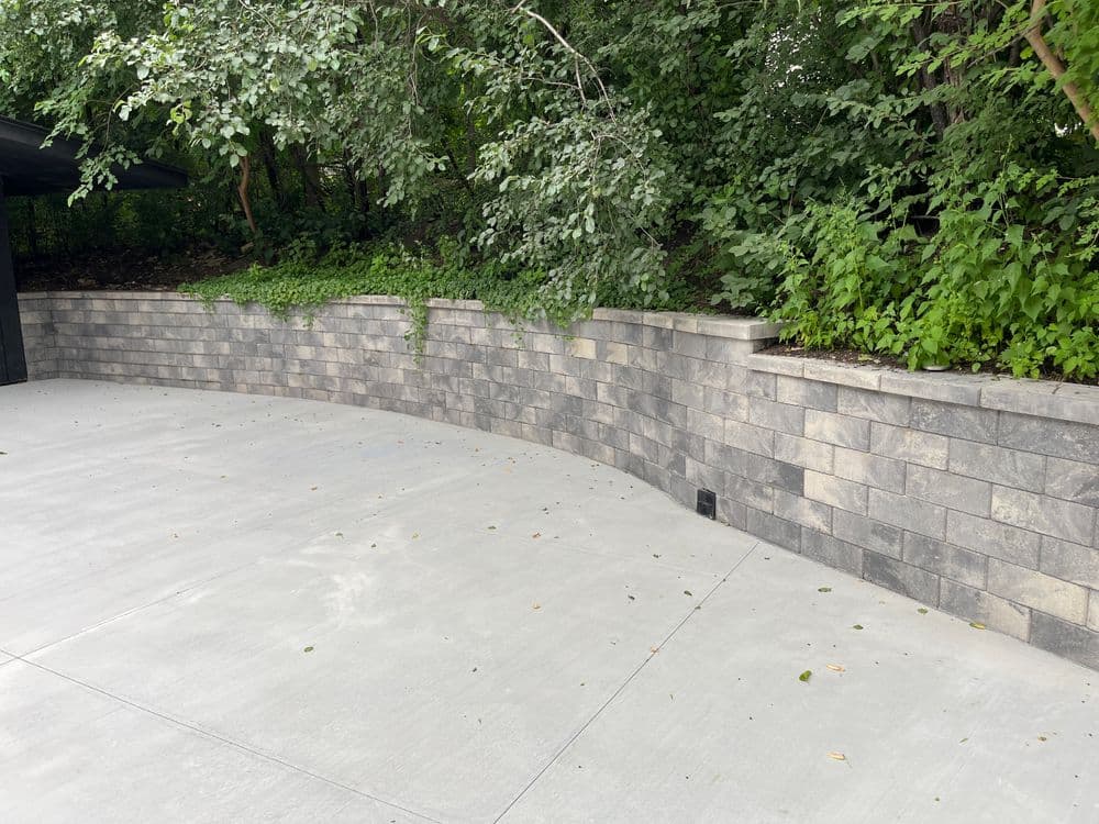 Curved stone retaining wall with greenery in a landscaped area.