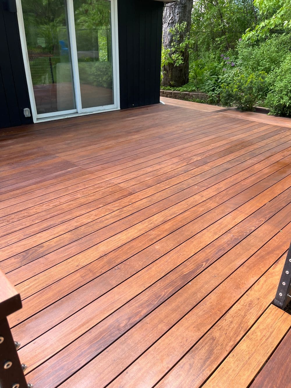 Newly installed wooden deck with rich brown tones and greenery in the background.