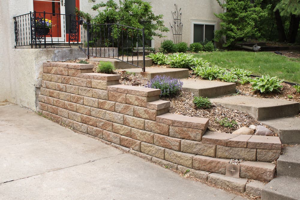 Landscape design featuring a stone retaining wall with steps, plants, and garden details.
